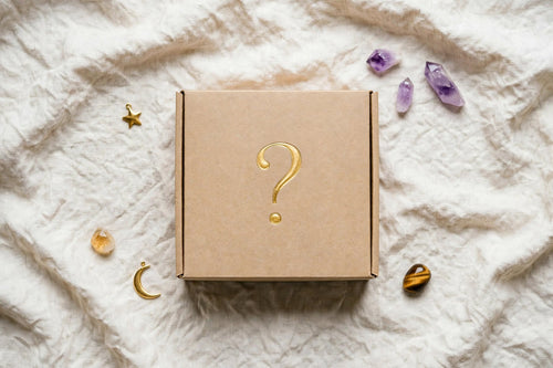 Box mystère kraft fermée avec point d'interrogation doré sur tissu lin beige avec améthyste, citrine et oeil de tigre
