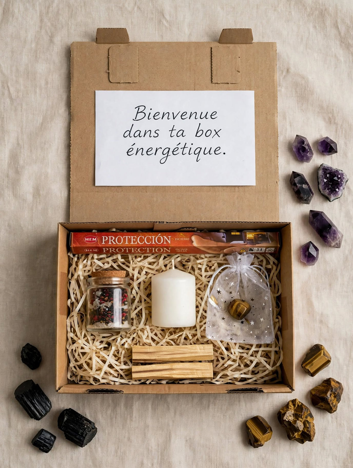 Box protection ouverte avec encens HEM protection, spell jar protection sel et poivre, bougie blanche, pierre oeil de tigre dans organza étoilé et palo santo sur frisure kraft
