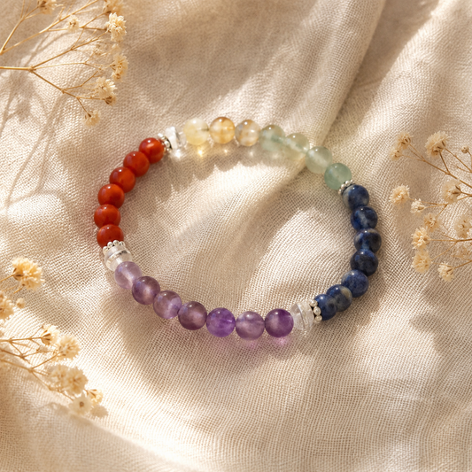 
Bracelet 7 chakras composé de perles naturelles multicolores, posé sur un tissu en lin beige avec des fleurs séchées.