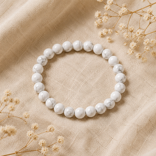 Bracelet en howlite blanche naturelle posé sur un fond en lin beige, entouré de fleurs séchées dans une ambiance lumineuse et épurée.