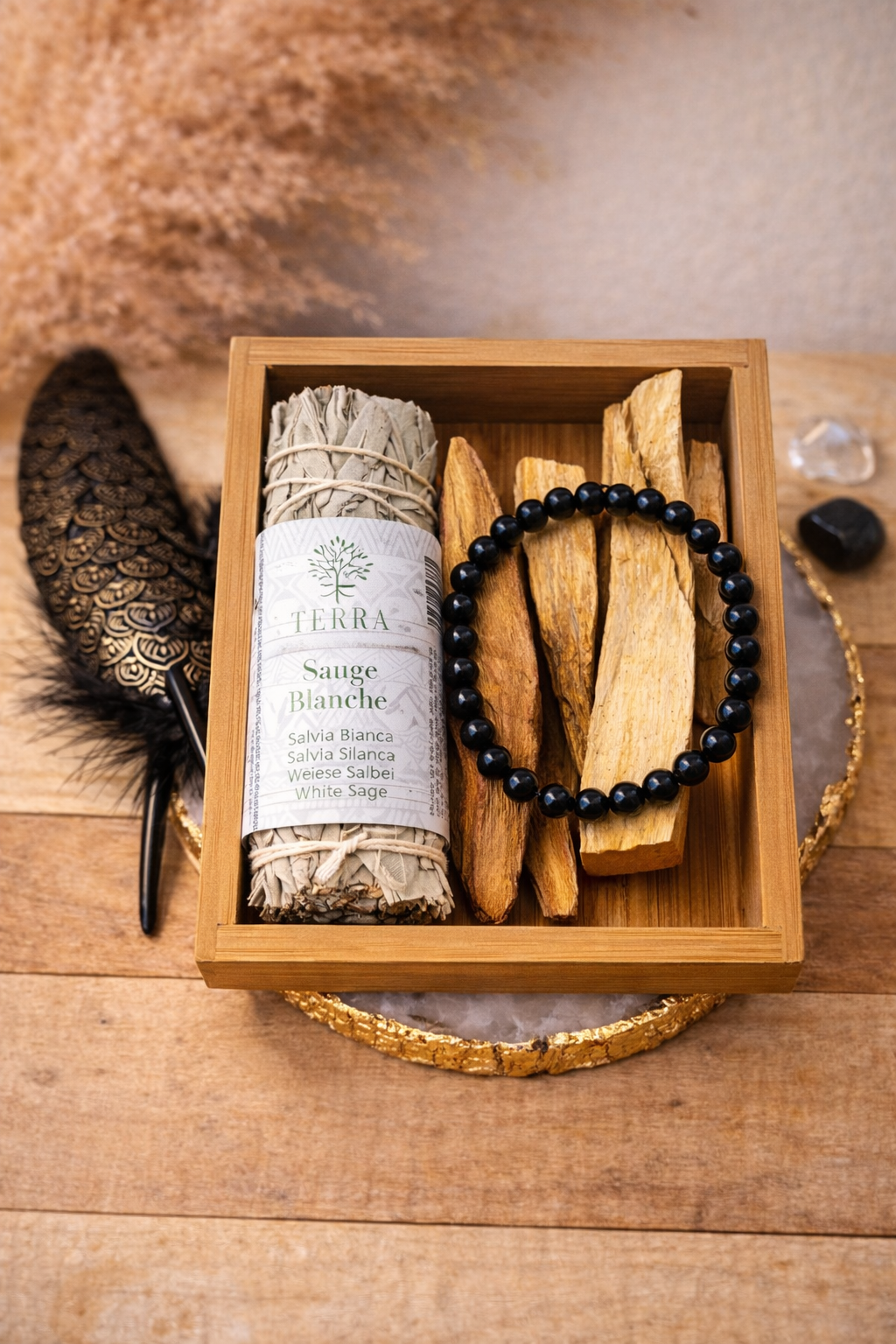 Coffret purification et ancrage avec sauge blanche, palo santo et bracelet en obsidienne noire présenté dans une boîte en bois dans une ambiance spirituelle.