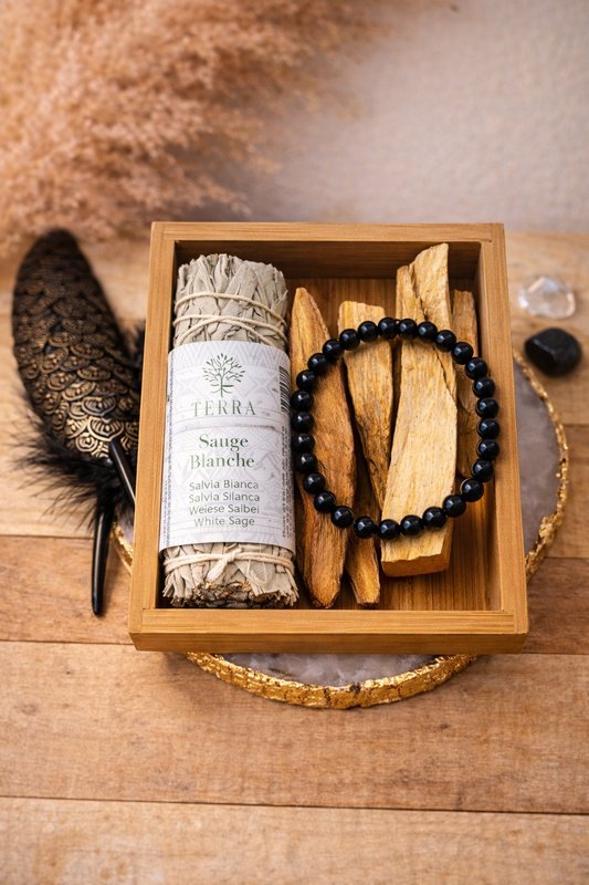 Coffret purification et ancrage avec sauge blanche, palo santo et bracelet en obsidienne noire présenté dans une boîte en bois dans une ambiance spirituelle.
