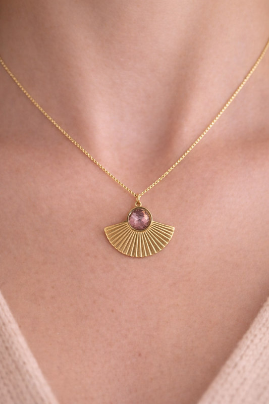 Collier doré porté autour du cou avec pendentif en forme de rayon de lumière et pierre violette, bijou fin et élégant. 