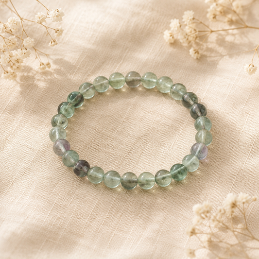 Bracelet en Fluorine verte naturelle posé sur un fond en lin beige, entouré de fleurs séchées.