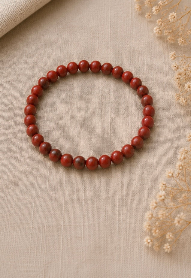 Photo posée :
Bracelet en jaspe rouge naturel posé sur un fond en lin beige, entouré de quelques fleurs séchées dans une ambiance douce et lumineuse.