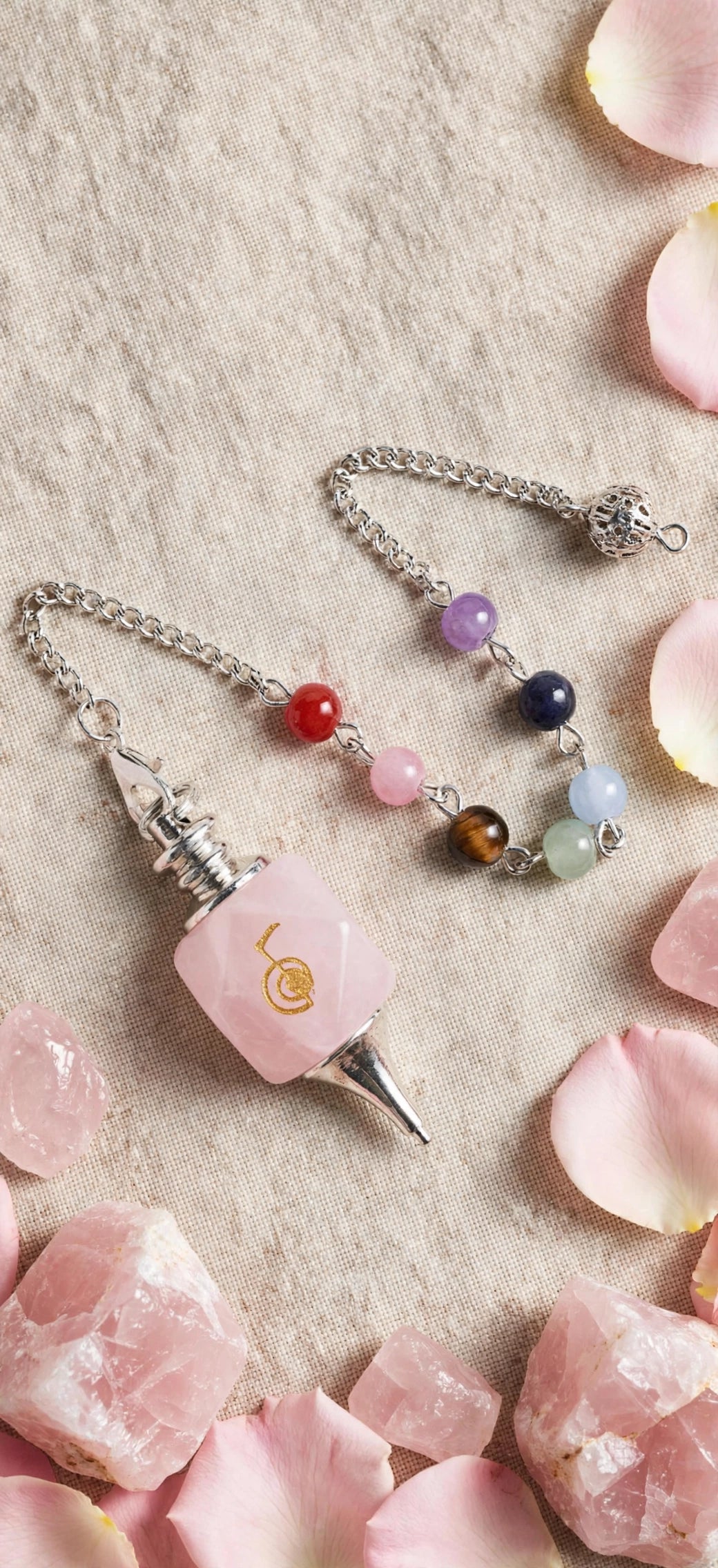 Pendule Quartz, rose, posée avec des pierres en rose et des pétales de roses